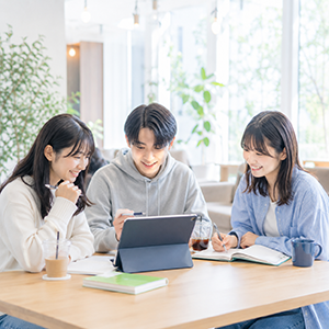カフェでタブレットを囲んで勉強する生徒たち